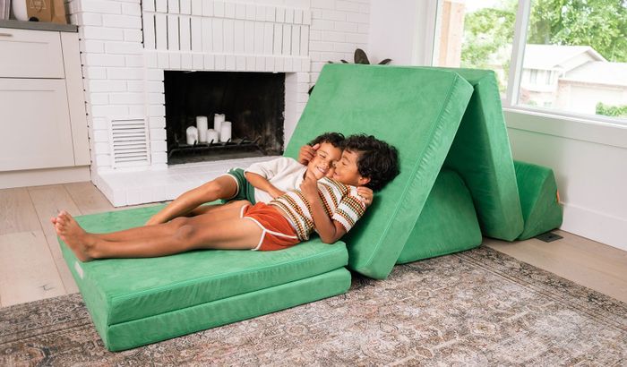 Two kids relaxing on a green Nugget couch.