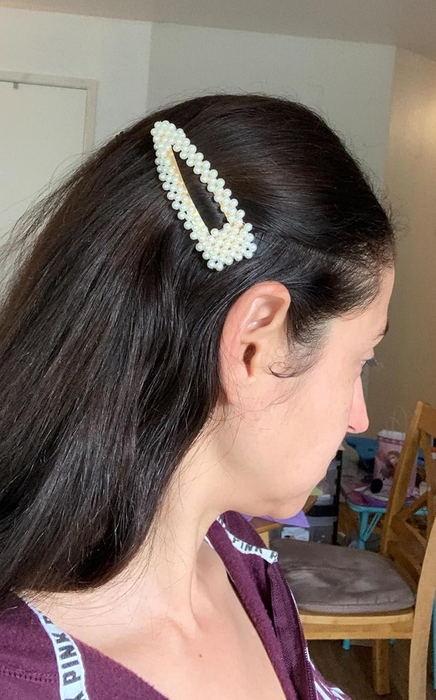 A reviewer wearing a large pearl-adorned hair clip.