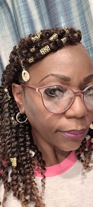 A person rocking gold cuffs in their twisted hair.