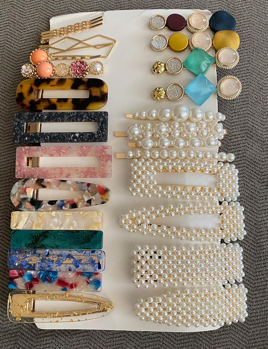 A collection of various hair clips and pins showcasing pearls, tortoiseshell, and colorful gemstones.
