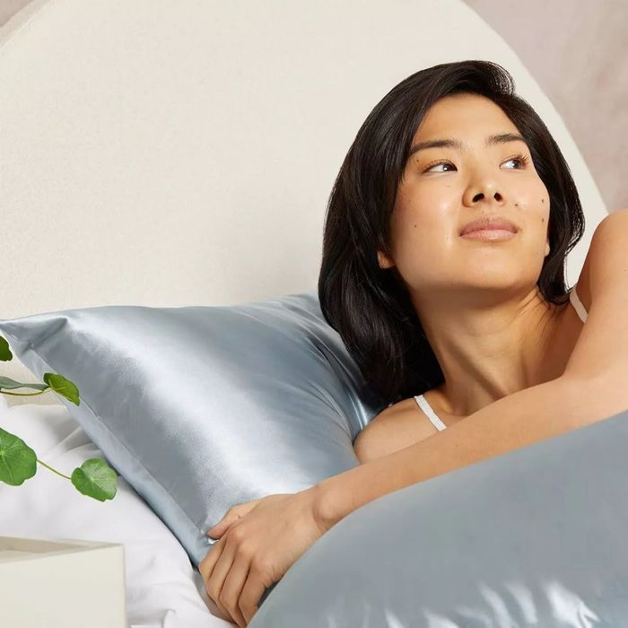 A model relaxes on the satin pillowcase, showcasing its luxurious feel.