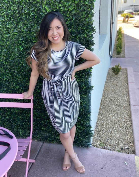 A reviewer in the black and white striped dress, with the belt cinched at the waist.