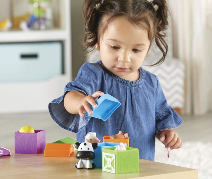 A child playing with educational farm-themed toys.