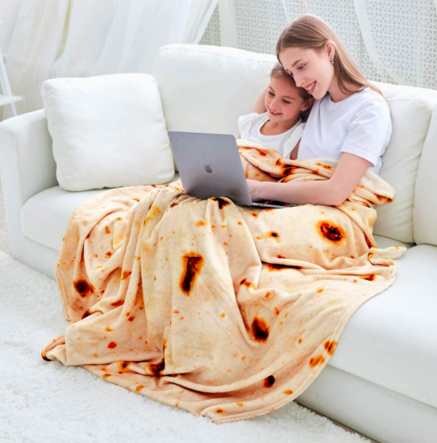 Models relaxing on a white couch with a blanket that resembles a tortilla