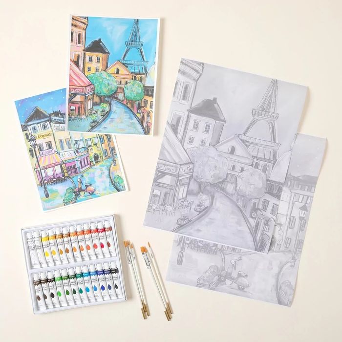 Art kit featuring watercolor paints, brushes, and illustrated sheets with beautiful cityscape designs.