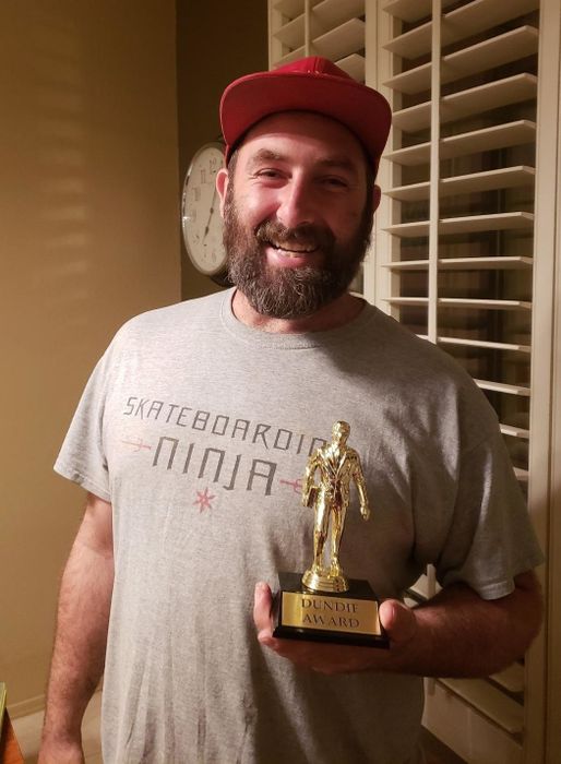 A reviewer holding their Dundie trophy proudly