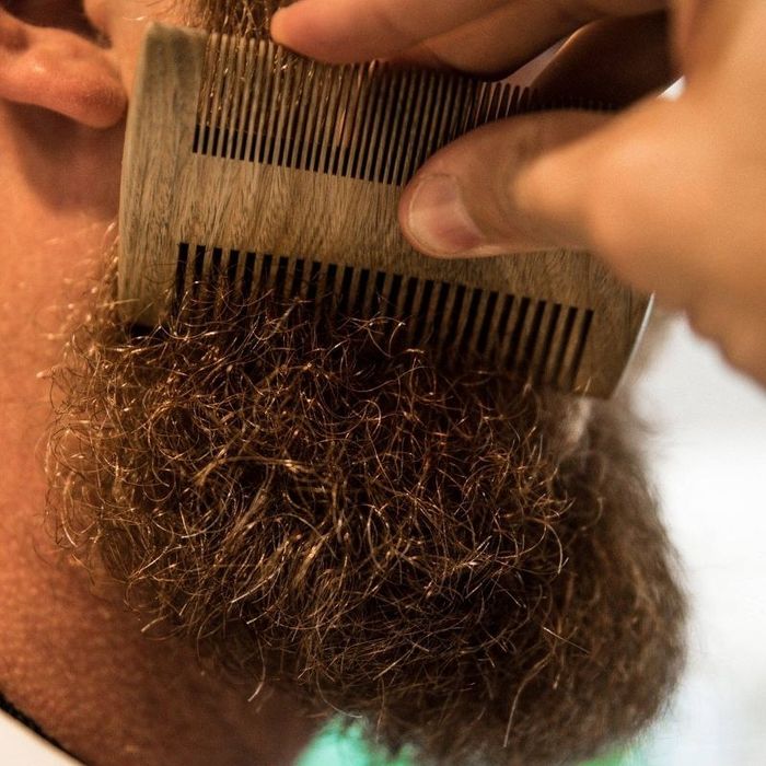The comb gliding through a mid-length curly beard.