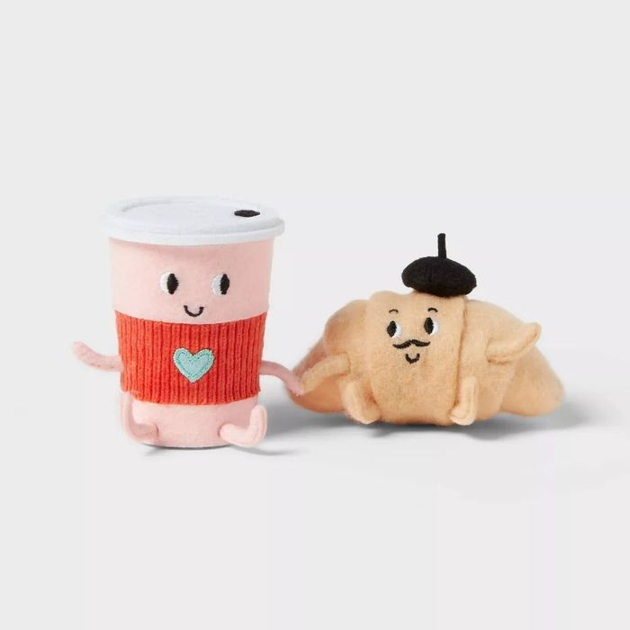 Adorable plush toys: a smiling coffee cup with a heart design and a playful croissant wearing a beret, highlighted in a shopping article.