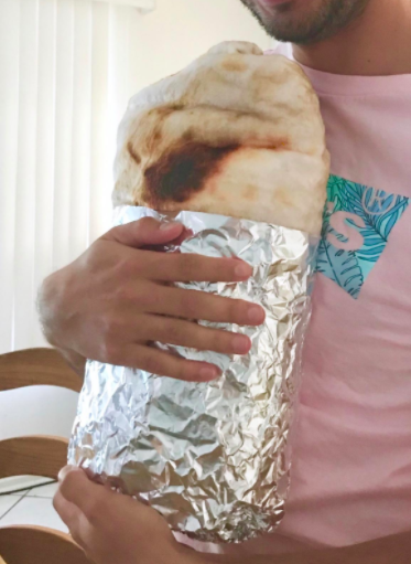 A reviewer holding a burrito blanket wrapped in real foil after receiving it as a gift