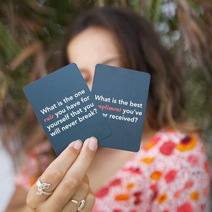 A model holding up two question cards, ready for the next round of the game.