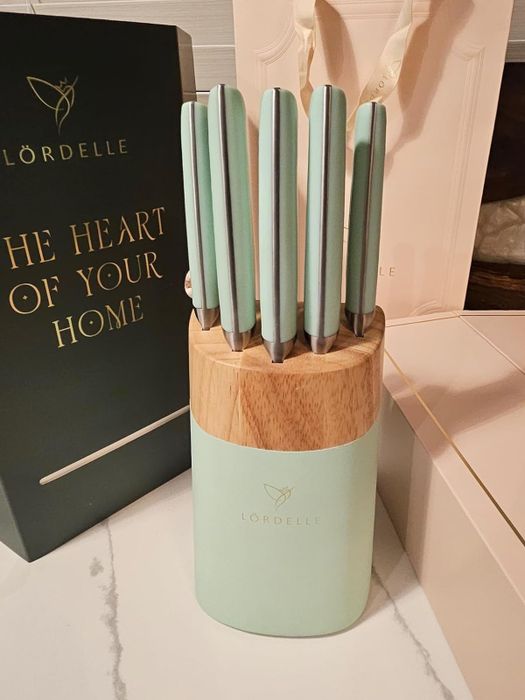 Lördelle knife set displayed with a wooden and mint green block on a kitchen counter, accompanied by its stylish branded packaging