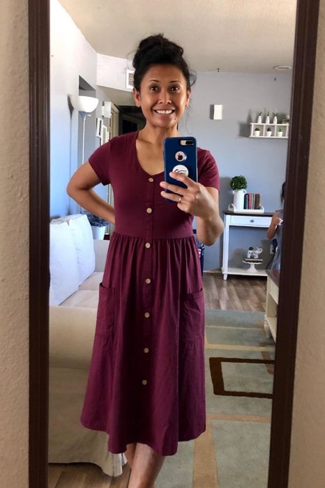 A reviewer takes a mirror selfie wearing a maroon dress.