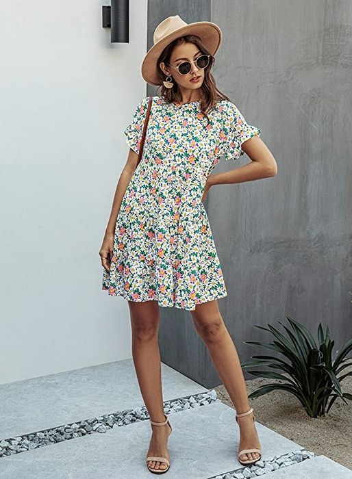 A model wearing a short sleeve floral dress paired with strappy sandals.