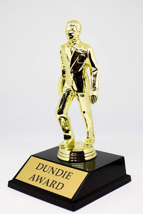 A gold businessman trophy with a plaque labeled 'Dundie Award'