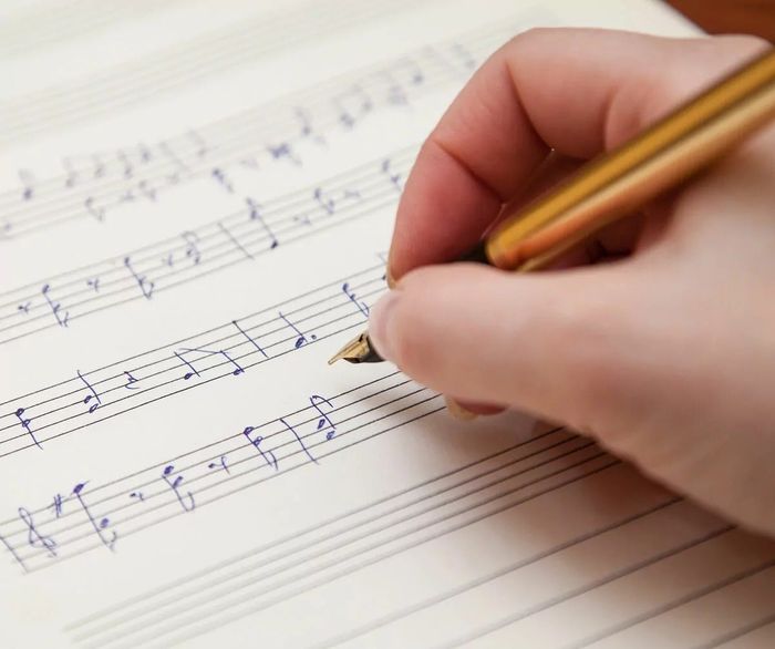 Handwritten music notes on sheet paper with a pen, focusing on composition or music theory.