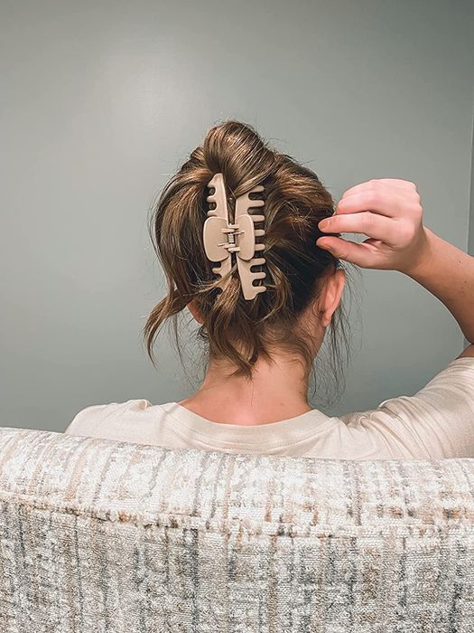 A person wearing a light pink claw clip in their light brown hair