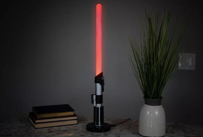 The red lamp casting a warm glow on a desk, surrounded by books and a plant