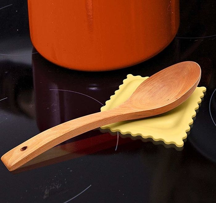 A wooden spoon placed on a yellow, ravioli-shaped silicone mat