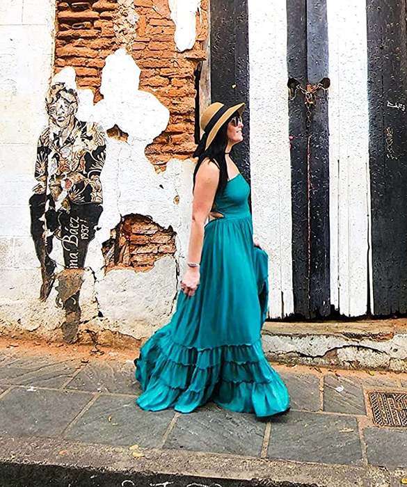A reviewer wearing a stunning long blue dress with an elegant open back