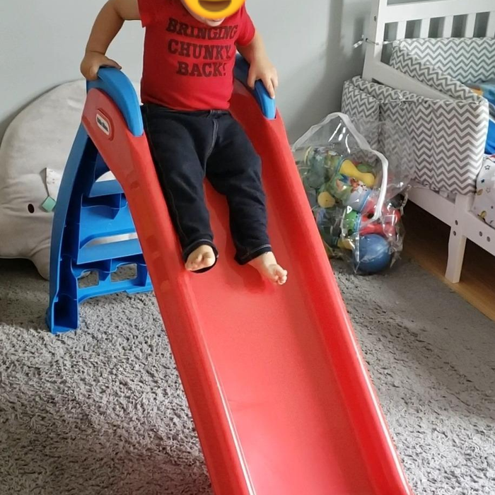A reviewer’s photo showing their child happily sliding down the red slide.