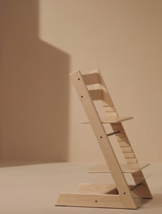 A stylish wooden highchair with adjustable seating and footrest, perfect for both children and adults, in a minimalist home setting.