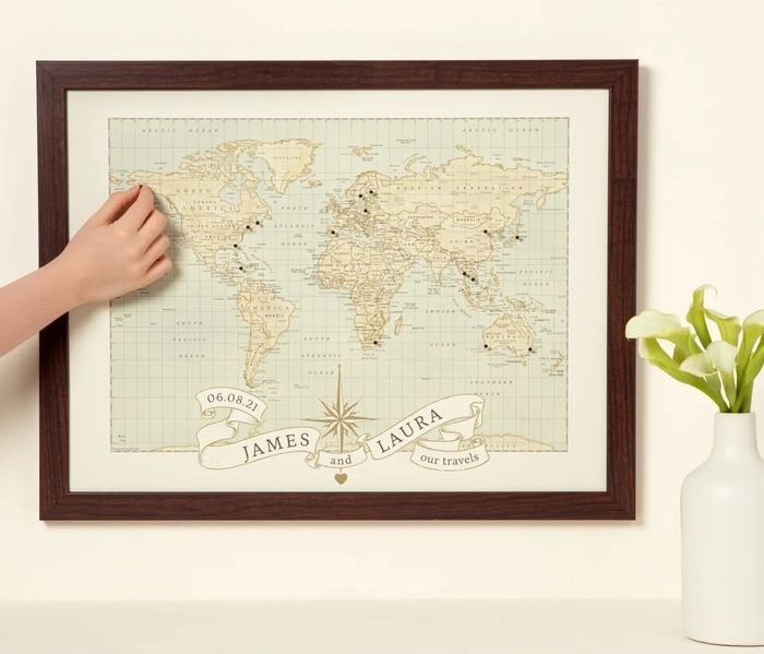 A hand pinning a framed world map with the banner
