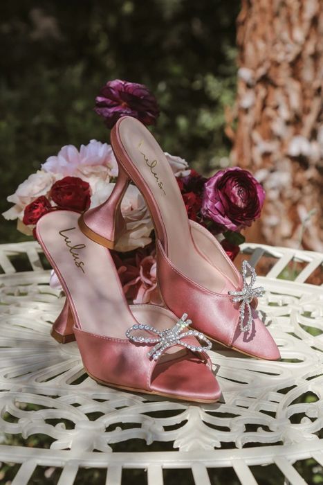 A pair of pink shoes beautifully arranged on a table, surrounded by flowers.