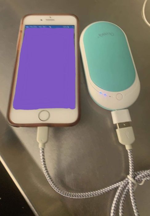 A reviewer using the hand warmer to charge their phone on the go