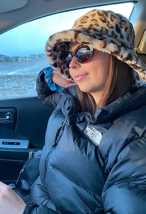 a reviewer sporting the leopard-print bucket hat while inside a car