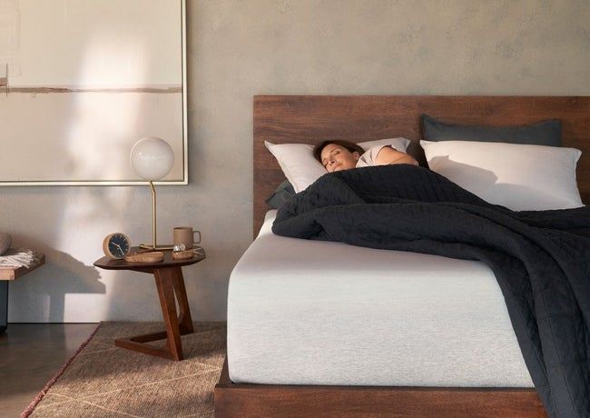 A thick white mattress with a model comfortably lying on top, enjoying a restful sleep in a serene bedroom