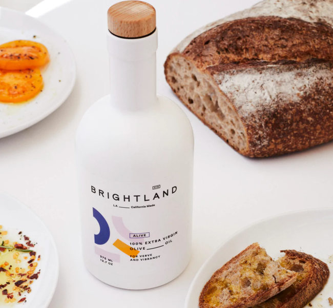 Close-up of a bottle of olive oil placed next to a slice of bread.