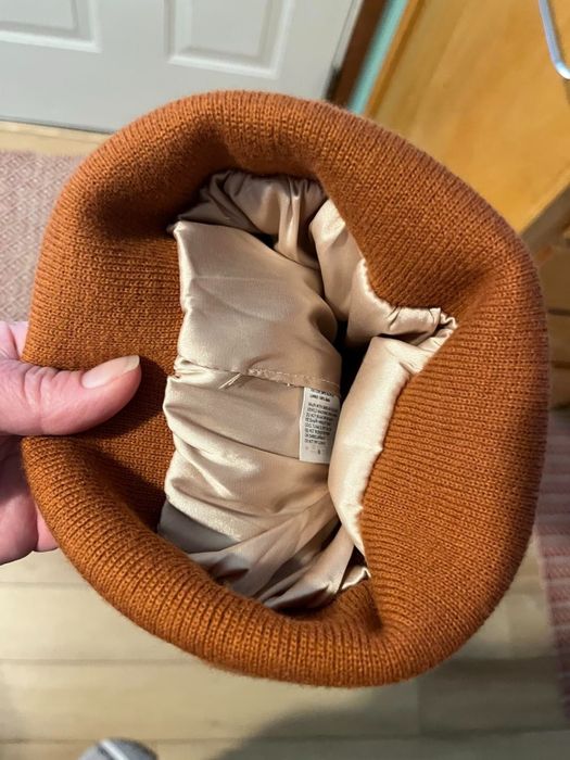 Reviewer’s photo showing a hand holding a brown beanie with satin lining inside