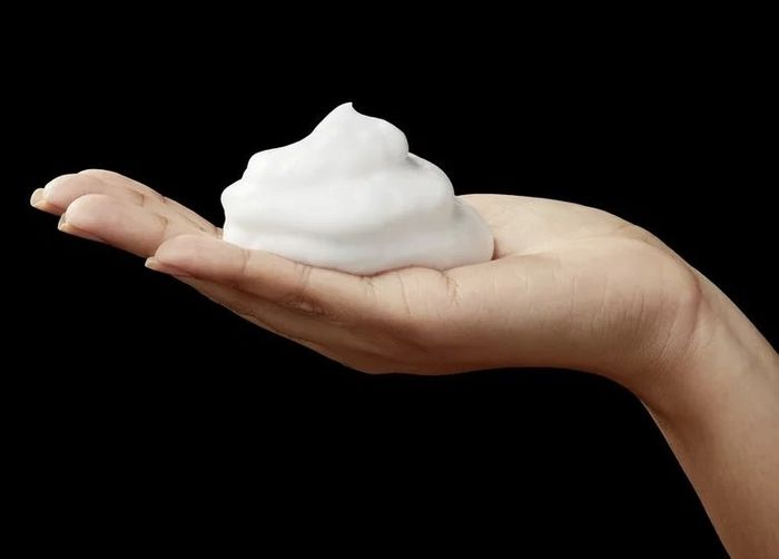 A model holding mousse in their hand