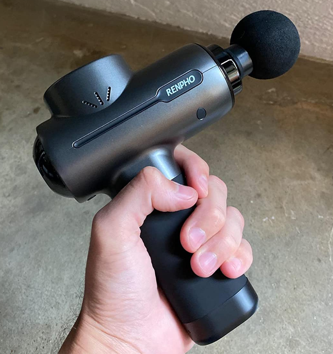reviewer holding the black massage gun