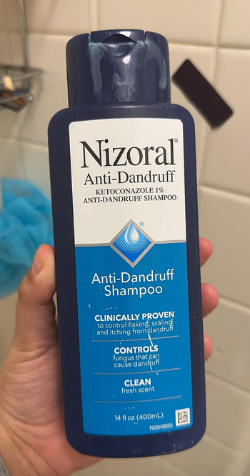 A reviewer holding a bottle of Nizoral.