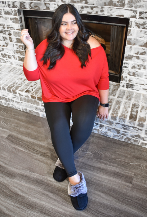 A reviewer enjoying the cozy black plush slippers at home.