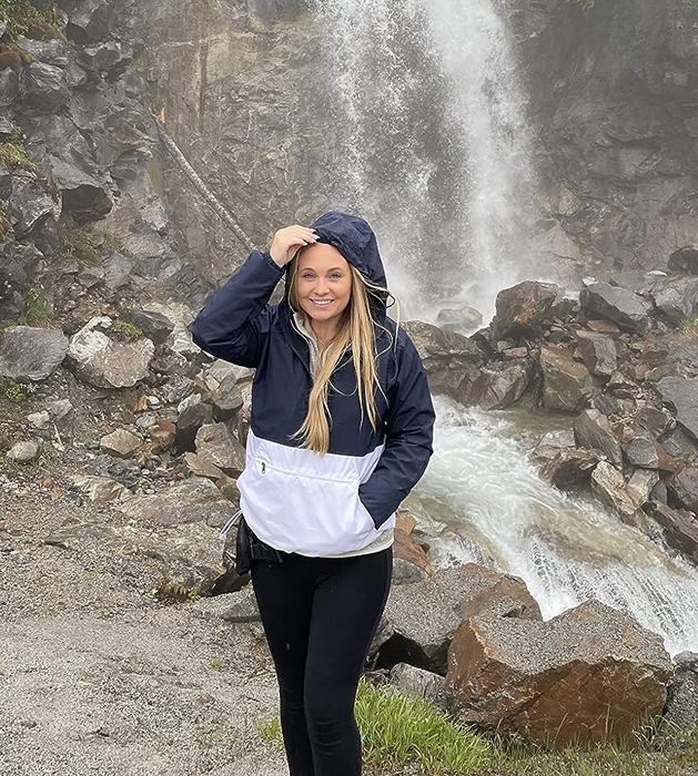 A reviewer models the navy blue and white jacket outdoors.
