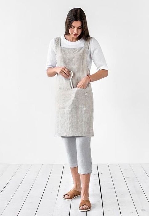 Model wearing the gray apron, placing a wooden spoon in its convenient pocket