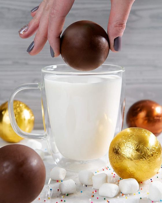 round hot chocolate bomb sinking into a glass of steaming milk