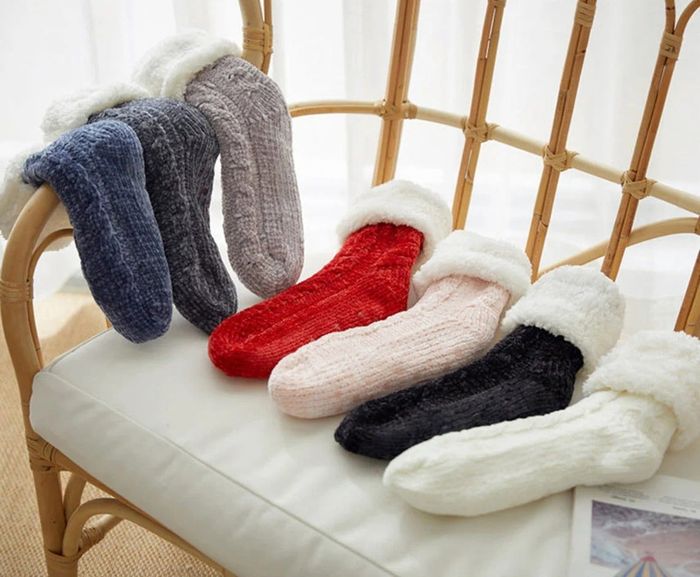 A variety of socks in blue, gray, red, and pink, neatly laid out next to each other on a chair.