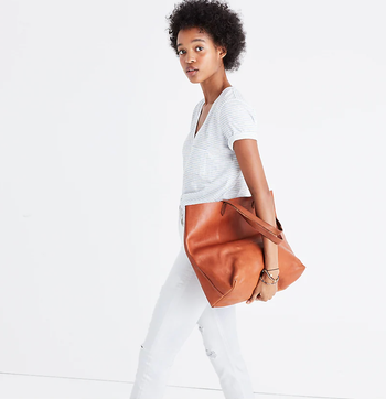 model carrying the tote in brown leather
