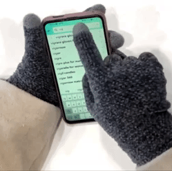 A gif showing someone easily using their phone while wearing the touchscreen gloves.