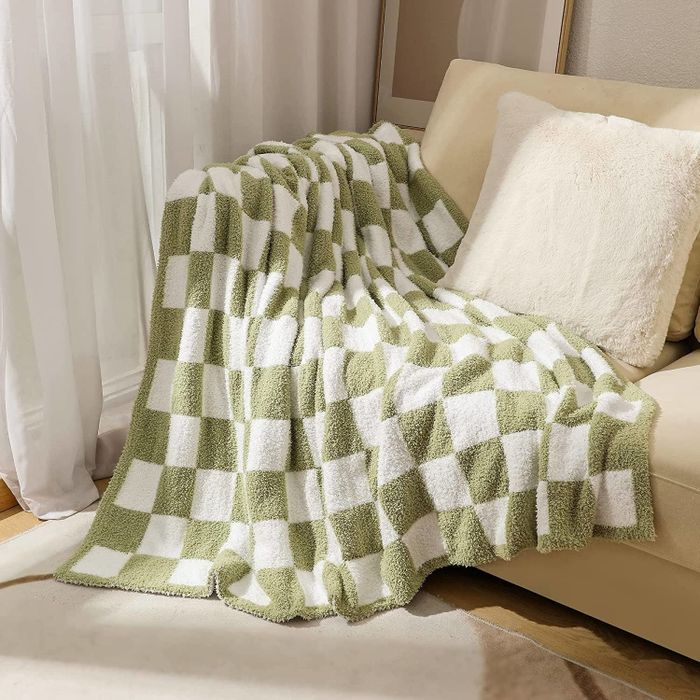 A green and white checkered blanket casually placed over a couch