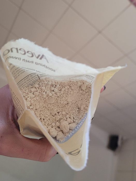 Reviewer holding an open packet of the bath treatment, showcasing its powder-like contents