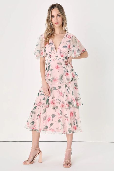 A model in a pink dress adorned with pink and green flowers.