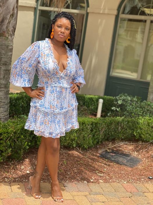 Reviewer wearing the same mini dress in white with a vibrant orange and blue floral print.