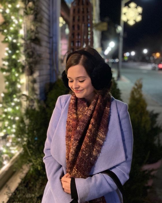 A reviewer showcasing black earmuffs as they walk through downtown.