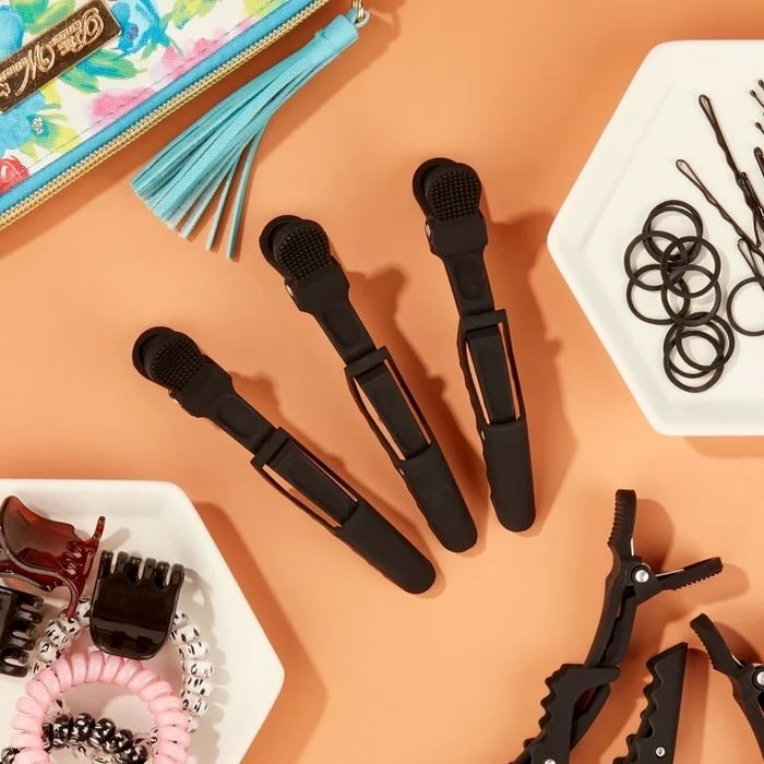 Black salon clips on an orange background, surrounded by other hair accessories