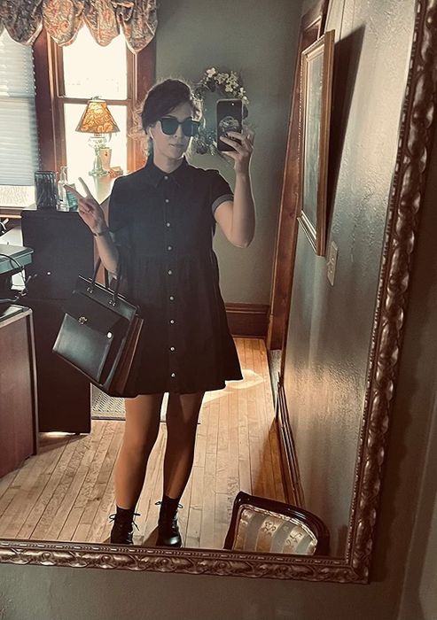 Reviewer wearing a dark blue, short-sleeved, button-down denim dress paired with ankle boots.