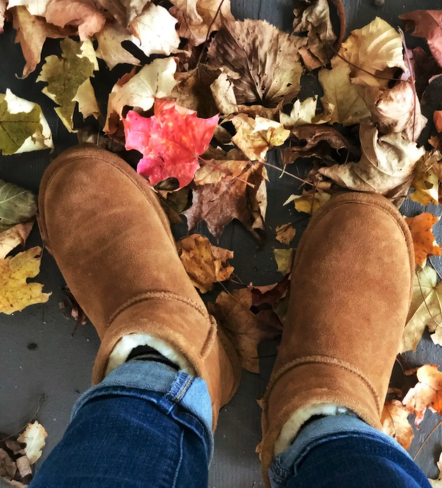 A reviewer rocking the boots while jumping in a pile of autumn leaves.